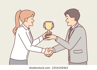 Boss presents cup to subordinate in recognition of achievement and shakes hands to motivate. Businesswoman receiving golden cup from partner after achieving high business performance