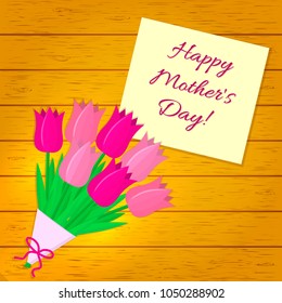 Bouquet of seven pink tulips, a sticker with text on the background of a wood texture. Congratulations. Mothers Day.