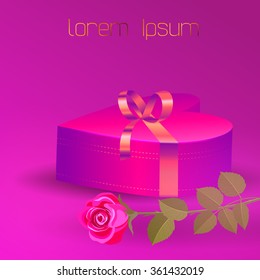 Box in form of heart with a gold bow on a pink background. Beside of the gift box is pink rose.