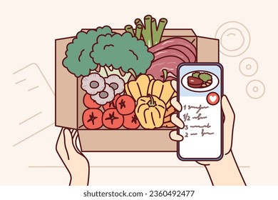 Box with fresh vegetables near mobile phone with application with healthy salad recipes for vegetarians. Organic vegetables delivered from farm store for health and diet conscious people