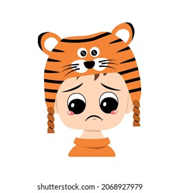 Boy with big eyes and depressive emotion, crying, tears face in tiger hat. Cute kid with sad face in a festive costume for New Year, Christmas and holiday. Head of adorable child with emotions