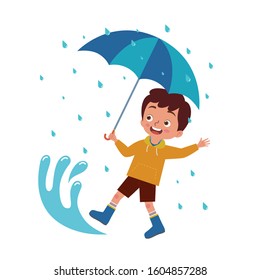 a boy carrying an umbrella playing happily in a puddle of rain