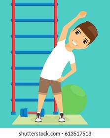 The boy is doing workout in the gym. Swedish wall. Sport and health promotion. Happy boy
