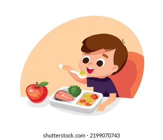 Boy eating healthy eco food with spoon sitting at the table. Child having meal for breakfast, lunch. Boy eats apple for supper, dinner or snack. Hungry kid have a meal. Meals are served to child.