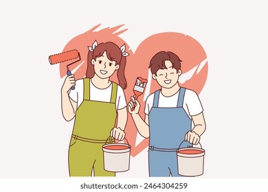 Boy and girl painted heart on wall using bucket of paint and roller with brush. Heart symbolizing love or kindness with charity, behind happy teenage children dreaming of becoming artists.