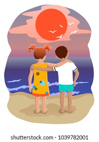 The boy and the girl stand in the arms of the sea and look at the sunset
