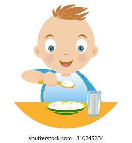 Boy having breakfast , holding a spoonful of porridge , a plate of porridge and a glass of milk on the table