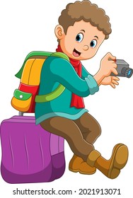 The boy is holding the camera and sitting on the suitcase of illustration