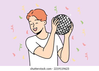Boy holds disco mirror ball in hands, smiles, dances at party. Red-haired guy having fun on holiday surrounded by falling confetti. Young man entertaining in nightclub. Vector linear illustration.