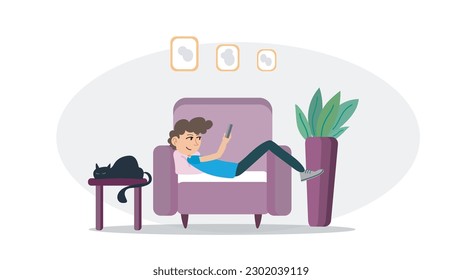 Boy is laying down on armchair and looking his telephone. Smiling boy with his telephone on armchair. Boy and his cat in living room laying down.