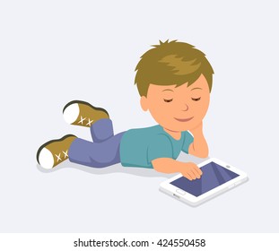 Boy lying down playing mobile games on the tablet. Learning, education and communication on the Internet using a mobile PC.