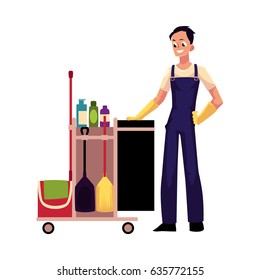 Boy, man, cleaner in overalls with cleaning trolley, cartoon vector illustration isolated on white background. Full length portrait of young man, boy with professional cleaning trolley