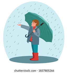 Boy with an open umbrella standing under the raindrops. Schoolboy with an umbrella in the rain. rainy day. Kid in autumn clothes in the fall, spring season, enjoying the rain and rainy weather.
