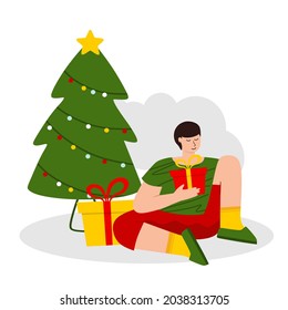 The boy opens gifts next to the Christmas tree. The concept of Christmas and New year. 