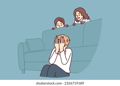 Boy plays hide and seek with friends sitting near sofa and waiting for other children to hide. Three cheerful children spend time together and enjoy weekend or summer school holidays