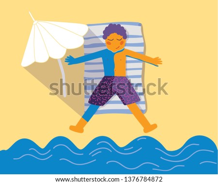Boy in purple shorts is lying on the beach and taking a sunbath