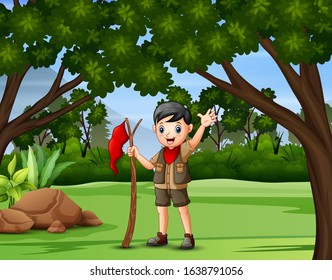 A boy scout holding a flag walking in forest