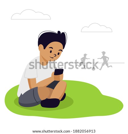 The boy is sitting on the grass in the park. He looks at his phone. His friends are playing football. He has a smartphone addiction, he does not play with them