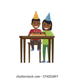 Boy sitting at table with birthday decorated cake with candles and elder girls stands near. Vector illustration of smiling children celebrating Happy Birthday in festive triangular caps on white