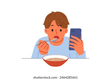 Boy suffering from digital addiction eats and watches video on mobile phone at same time. Schoolboy needs help of psychologist to combat addiction to phone and use of social networks