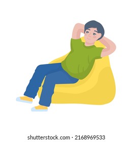 Boy wearing green t-shirt sits in bag chair stretch hands isolated on plain yellow background. Lifestyle concept.