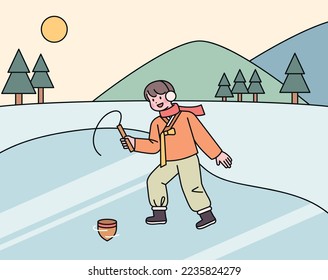 A boy wearing a hanbok in the cold winter is playing tops on the ice.