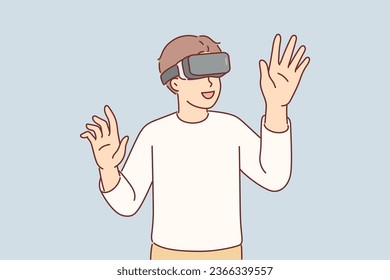 Boy wearing VR glasses enthusiastically uses new technology to immerse himself in virtual reality with 3d effect. Amazed kid plays VR game and raises hands to touch invisible objects