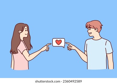 Boyfriend and girlfriend experience love and surge of romantic mood and point to heart icon together. Concept of mutual first love between boy and girl of adolescence dressed in casual clothes