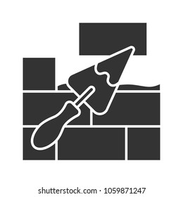 Brick wall with triangular shovel glyph icon. Putty knife, spatula. Cement solution. Silhouette symbol. Negative space. Vector isolated illustration