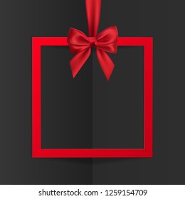 Bright holiday gift box frame banner hanging with red ribbon and silky bow on black background. Vector illustration.