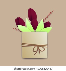 Bright red tulips in a square pot with a rope and a tiny bow. There are springs and leaves also.