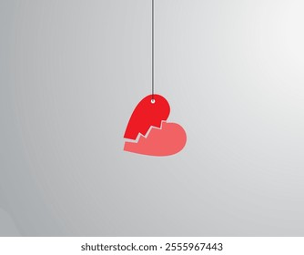 a broken heart hanging suspended by thread against gray background