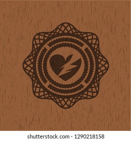 broken heart icon inside badge with wooden background