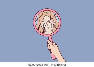 Broken mirror in hand of crying woman and reflection of face of emotionally unstable person in need of antidepressants. Crying girl suffers from bullying or shaming and violation of women rights