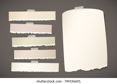 Brown horizontal ripped strips, notebook, note paper for text or message stuck with sticky tape on dark gray background.