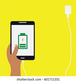  brown human hand vector illustration charging a black cell phone & mobile. screen with battery plugged in charging on a flat design yellow background and a place or space to write