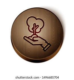 Brown line Tree in hand of environmental protection icon isolated on white background. Seed and seedling. Planting sapling. Ecology concept. Wooden circle button. Vector Illustration