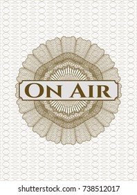 Brown money style emblem or rosette with text On Air inside