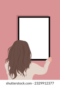 Brunette woman with her back hanging a picture on the wall.