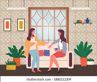 Brunette women sitting at sofa and talking. Friends relaxing at home with a cup of tea or coffee. Happy spending leisure time at home. Sisters talking, relaxing at couch near window in living room