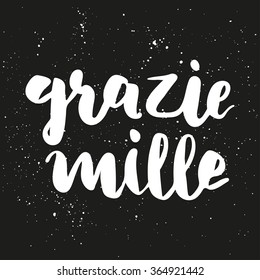 Brush lettering composition. Phrase - Thanks a lot in italian - on dark gray background with white ink splashes.