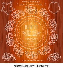 Brush set.Calligraphic element border.Pattern frame of the branches of the flowers. Wooden background. Hand drawn Floral ornament of leaves and flowers.Vintage style.Vector.