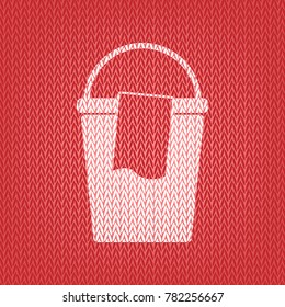 Bucket and a rag sign. Vector. Knitted white icon on a red knitted background.