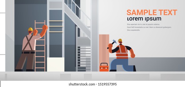 builders couple using hammer and ladder busy workmen team in uniform working together building concept construction site interior rear view flat full length horizontal copy space