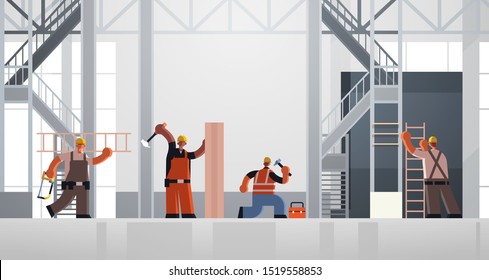 builders using hammer and ladder busy workmen carpenters team in uniform working together building concept construction site interior flat full length horizontal