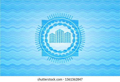 buildings icon inside light blue water wave style badge.