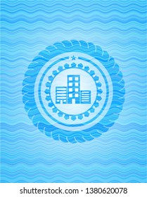 buildings icon inside light blue water wave badge.