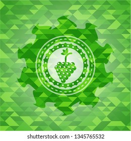 bunch of grapes icon inside green emblem with triangle mosaic background
