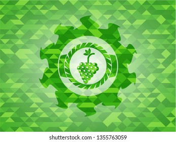 bunch of grapes icon inside green emblem with triangle mosaic background