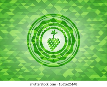 bunch of grapes icon inside green emblem with mosaic ecological style background
